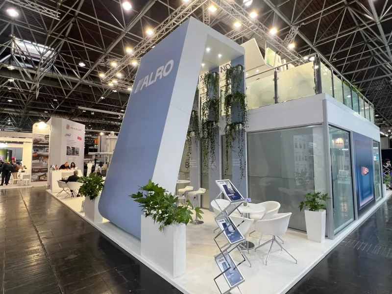 Corner view of the ALRO double-decker stand with upper deck, glass balustrade and plants